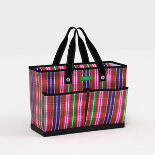 A structured open-top tote bag in a multicolor plaid print of hot pink, navy, green, red, and white, with two exterior front pockets, black webbing handles, and a solid black reinforced base.