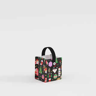 A small structured square gift bag with a black background covered in a multicolor holiday character print including Santa, snowmen, ornaments, and Christmas trees, with a short black webbing handle and a snap closure at the top.