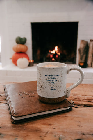 Mug with text on a wooden surface in front of a fireplace